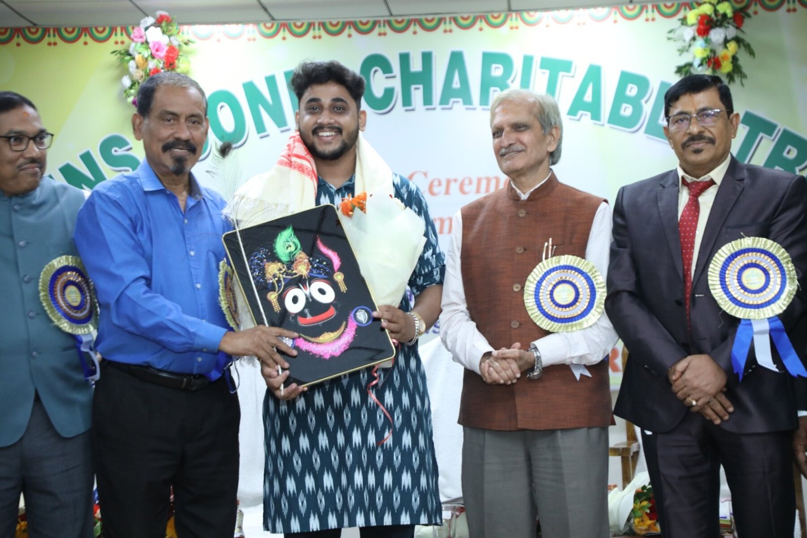 Dignitaries on stage at the official launch ceremony of Brains Iconic Charitable Trust, each holding a Jagannath-themed artwork, beneath a decorated Opening Ceremony banner.