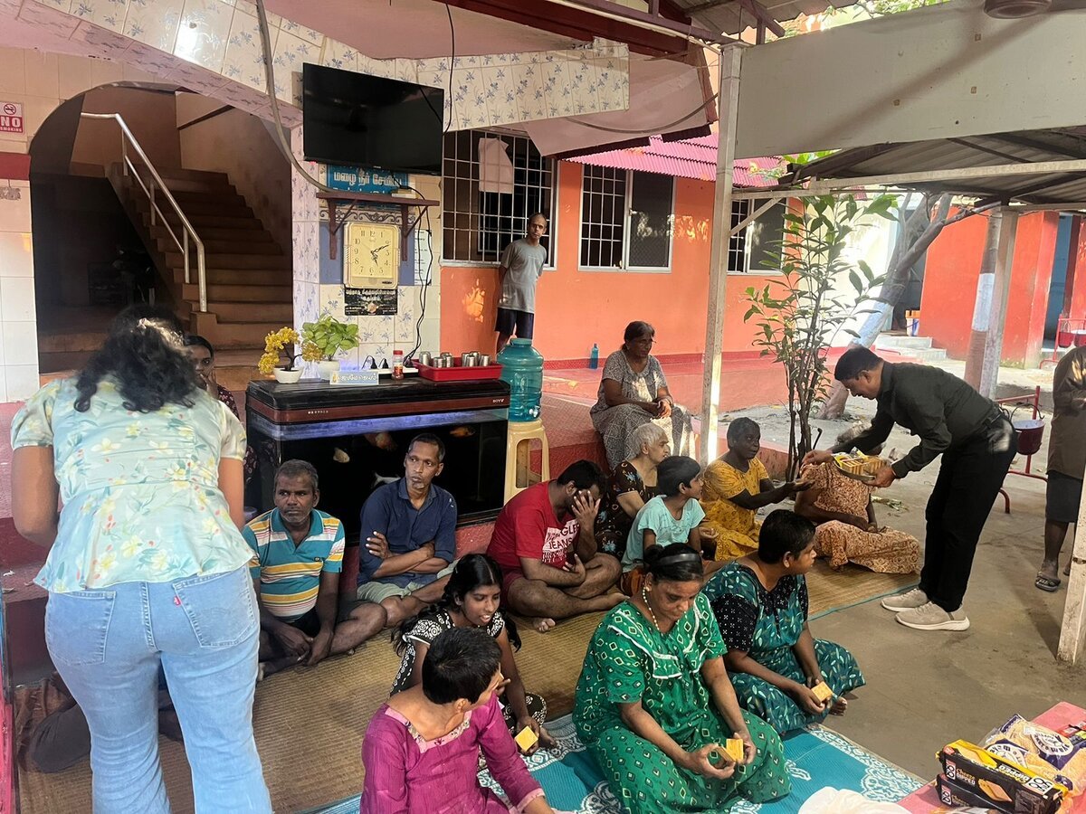 Volunteers distributing snacks and essentials to elderly and differently-abled residents at a care home.