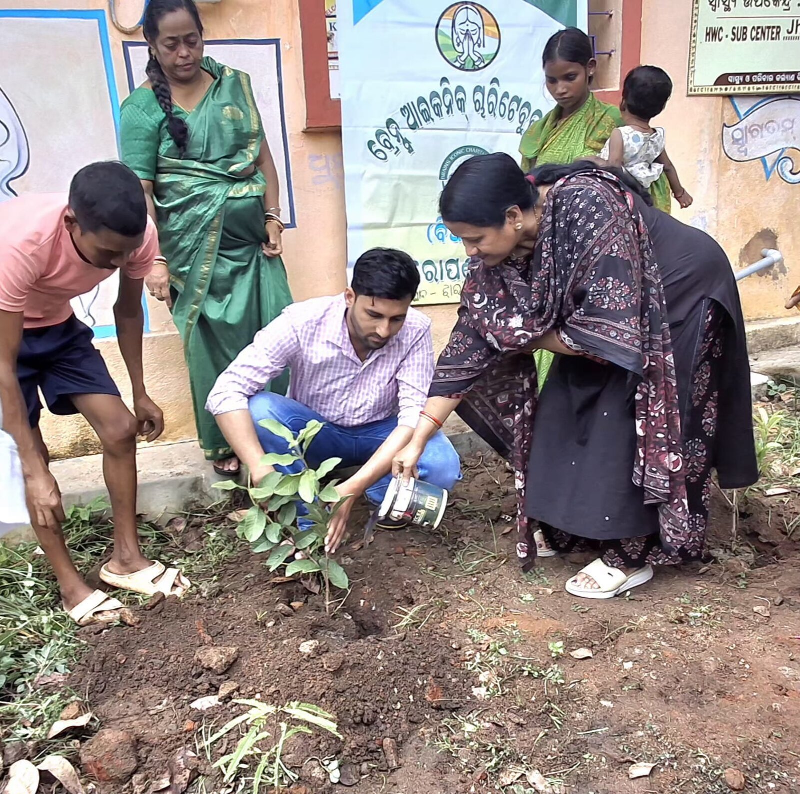 A close moment as volunteers and a community member plant a sapling together.